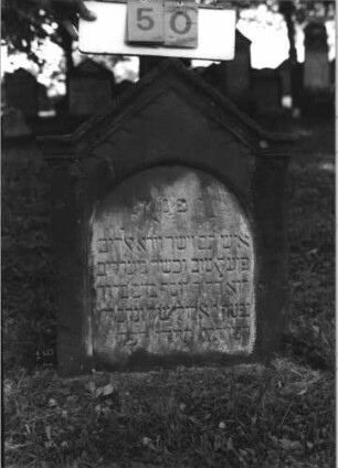 Grabstein 50 (Index: 100113798) Material: Sandstein Zustand: mittelstark verwittert Maße HxBxT: 74x58x13 cm Beschreibung: Stele mit eingezogenem Spitzgiebel, vertiefter Textteil in Form einer Stele mit Rundbogen: Grabstein 50