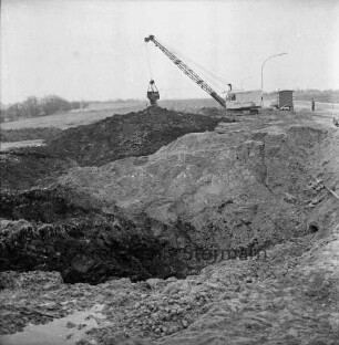 Industriestraße: Absackung eines Teilstücks: vorn Abbruchkante mit Grube: dahinter Erdhaufen: rechts Bagger, Arbeiter und Baubude