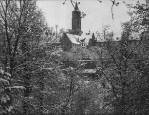 Verschneite Stadt : Blick durch Äste auf schneebedeckte Gebäude einer Stadt