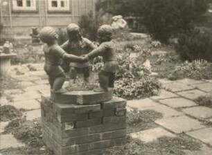 Drei Kinder bei Ringelreihen: Gartenskulptur: Rohlfshagen, Kupfermühle: Schäferkate, im Garten, auf Backsteinsockel: hinten weitere Skulpturen
