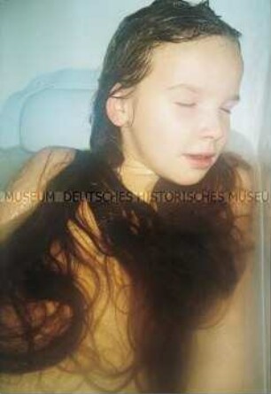 Mädchen mit geschlossenen Augen in der Badewanne liegend (Altersgruppe bis 14)