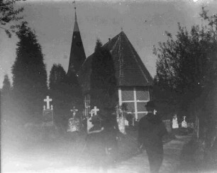 Friedhof um eine Fachwerkkirche mit Passanten