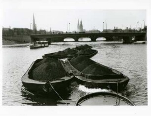 Hamburg. Ein mit Kohle beladener Schleppverband auf der Aussenalster. Im Hintergrund die Kennedy- und Lombardsbrücke sowie die Silhouette der Innenstadt mit ihren prägnanten Türmen.