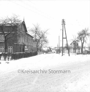 Rethwischdorf: Dorfplatz: Hauptstraße: Bundesstraße B 208 mit Kopfsteinpflaster: links Bäume: dahinter Bauerngehöft Spiering: rechts Strommast: dahinter Bauernhäuser: Winter