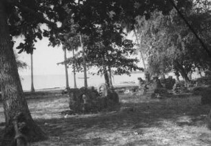 Araber-Friedhof in Kilwa : Blick in eine Landschaft am Strand mit Palmen, Bäumen und arabischen Gräbern. Im Hintergrund Meer mit Booten