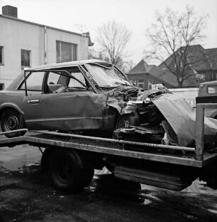 Hof des Abschleppdienstes am Waldemar-Bonsels-Weg: nach Verkehrsunfall: Wrack von Unfall-Pkw auf Plattform von Abschleppwagen: rundum abgestellte Pkws: hinten links: Werkstattgebäude, hinten Mitte: U-Bahnhof Ahrensburg West