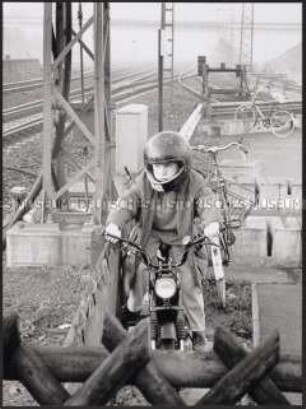 Kleiner Junge auf dem Moped neben Bahngleisen (Altersgruppe bis 14)