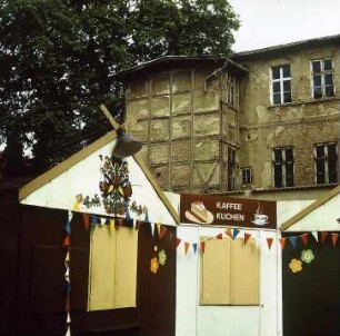 Geschlossene Volksfestbuden vor Hausruine