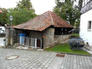 Kirchhof im Nordnordosten mit erhaltener Basis eines Steingaden (Kellereingang erhalten-feste Kirchhofmauer als Außenmauer)