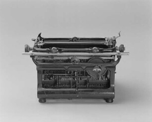 Typenhebelschreibmaschine "Ideal" (Modell C). Vorderanschlag (sofort sichtbare Schrift), Farbband. Rückansicht