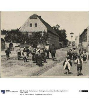 Musikanten und Kinder gehen durch das Dorf, Coswig