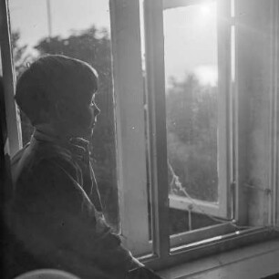Das Kind der Gremmlers sitzt am geöffneten Fenster