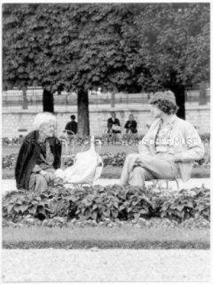 Junger Mann und alte Frau im Park im Gespräch (Altersgruppe 18-21)