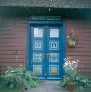 Darß. Haus mit traditionell geschnitzter und bemalter Haustür, darüber ein Spruch