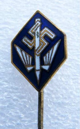Verbandsabzeichen Deutsche Stenografenschaft (mit langer Nadel) : Sammlung Beinhorn. Verbandsabzeichen Deutsche Stenografenschaft (geflügelte Feder und Hakenkreuz auf blauem Grund, mit langer Nadel; rückseitig: Ges. Gesch.). Email, Metall; Maße (ohne Nadel) 15,5 x 11 mm (1933/1943). Dresden: SLUB R c 0175
