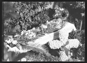 Toter im offenen Sarg mit Blumenschmuck
