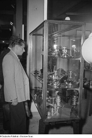 Fachbesucher vor einer Vitrine mit Kameraobjektiven