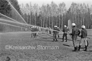Großübung: Festplatz Klein Wesenberg: Feuerwehrmänner mit Feuerwehrschläuchen beim Löschen: im Hintergrund Bäume