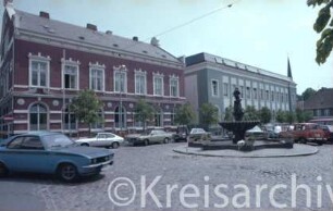 Markt: Gänseliesel-Brunnen: parkende Autos: dahinter von links Stadthaus, Postgebäude: hinten rechts Hindenburgstraße, im Hintergrund Turm von Peter-Paul-Kirche: im Vordergrund links Hagenstraße