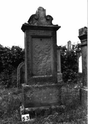 Grabstein 53 (Index: 99891685) Material: Sandstein Zustand: Inschriftentafel zerstört Maße HxBxT: 175x72x49 cm Beschreibung: rechteckige Stele auf Sockel, Mittelakroter Symbolik: Blüte in Mittelakroter: Grabstein 53