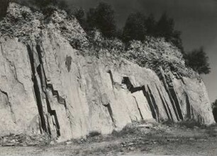 Rochlitzer Quarzporphyr. Großplattig (saiger) abgesondert mit Überlagerung von Pleistozän (Geschiebelehm). Steinbruch am Kiefernberg südöstlich von Dornreichenbach