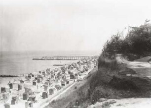 Blick vom Steilufer über den Strand mit Strandkörben gegen die Seebrücke in der Ostsee