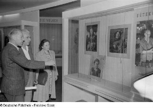Besucher der Technischen Messe 1953 stehen vor einer Vitrine mit Kunstdrucken