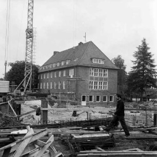 Woldenhorn-Schule: Sonderschule des Kreises Stormarn für geistig behinderte Kinder: Ecke Reeshoop / Schulstraße: Erweiterungsbau: in Bau: Baugrube mit Verschalungen für Fundamente: Arbeiter, Bretter, Baustahl-Armierungen, Aushub: Baukran, Bretter an Haken: hinten Altbau: Blick von Hans-Schadendorff-Stieg aus