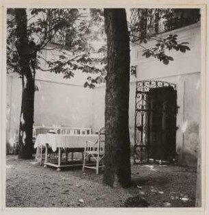 Garten von Hofmannsthals Rodauner Haus, Terrasse im Innenhof mit zwei Bäumen (Kastanien), Gartentisch mit Stühlen