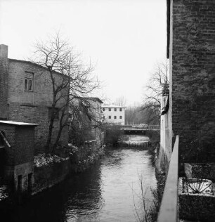 Trave: rechts und links Gewerbegebäude: links Bäume: hinten Brücke mit Pkw: dahinter Mitte Gebäude