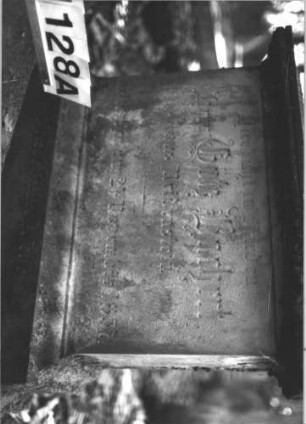 Grabstein 1128 (Index: 99899818) Material: Sandstein Zustand: Sockel leicht verwittert, Stele liegt Maße HxBxT: 220x75x32 cm Beschreibung: aufgesockelte Stele mit eingezogenem Rundbogenabschluss, Einzüge akroterienhaft erhöht, vom Sockel gestürzt, liegt: Grabstein 1128A