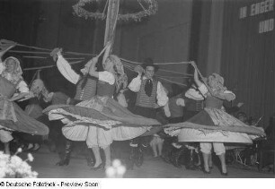 Menschen in Tracht tanzen bei einer Veranstaltung zum Gedenken an die Völkerschlacht mit Bändern in der Hand um einen Maibaum