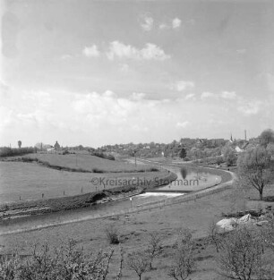 Trave: in der Mitte Sohlabsturz unterhalb der Lübecker Straße: vorn Streuobstwiese: hinten links Wasserturm und Silo am Bahnhof: hinten rechts Gebäude und Turm der Peter-Paul-Kirche