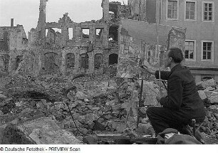 Theodor Rosenhauer arbeitet zwischen Trümmern an seinem Ölgemälde "Blick auf das Japanische Palais nach dem Angriff"