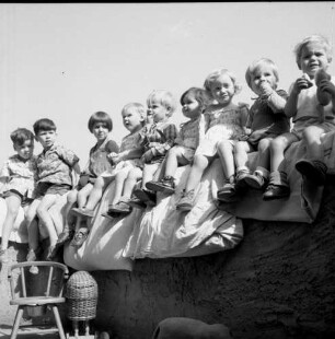 Glauburg-Glauberg (Wetteraukreis). Kinderheim? Kinder mit Bettkissen auf einer Mauer sitzend