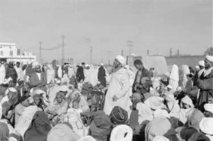 Reisefotos Marokko. Straßenkünstler mit Zuschauern während einer Vorführung. Im Hintergrund Teilansicht des Gebäudes "Minoterie algerienne" (vielleicht in Casablanca)
