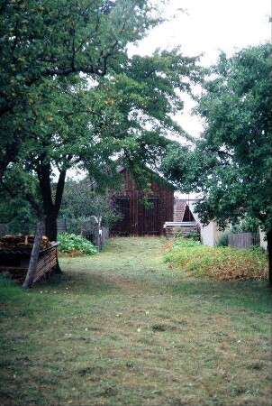 Garten mit Obstbäumen, Wiese und Beeten, hinten Scheune