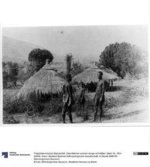 Zwei Männer und ein Junge vor Hütten