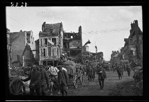 Péronne (?) (Dep. Somme, Frankreich): Soldaten und Fuhrwerke auf einer morastigen, gepflasterten Ortsstraße zwischen Gebäuderuinen (Vorderansicht)