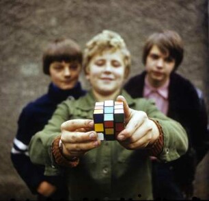 Zauberwürfel : Portrait von drei Jungs. Focus auf den Zauberwürfel (Rubiks Cube) in den Händen des Mittleren Jungen