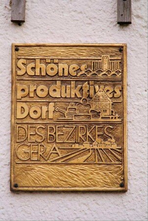 Schild am Gemeindeamt "Schönes produktives Dorf DES BEZIRKES GERA"