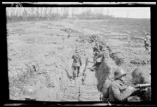 Übungsgelände I bei Mouzon (Dep. Ardennes, Frankreich): brusthoher Graben mit Knüppelweg, darin Soldaten mit Stahlhelm und aufgelegten Gewehren ("im Graben")