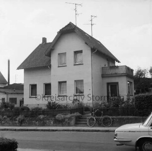 Stadtvilla: rechts Anbau mit Balkon: davor Vorgarten, Zaun, Fahrrad: vorn Straße: rechts Heck eines Pkws