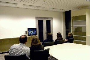 Besucher vor dem Monitor in einem Seminarraum