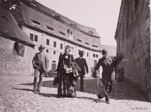 Donadini, Ida : Frau Ida Donadini mit Bekannten im Hof der Burg Wettin, der rechte eine Stereokamera tragend