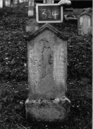 Grabstein 324 (Index: 100090386) Material: Sandstein Zustand: abgeblättert mit Textverlust Maße HxBxT: 85x40x9 cm Beschreibung: Stele, Sockel, eingezogener giebelartiger Abschluß mit Verdachung: Grabstein 324