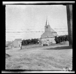 Unbekannte Ortschaft [Nordfrankreich?]: kleine Ortskirche mit Friedhofsmauer (Distanzaufnahme)