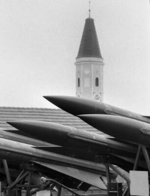 Sprengköpfe von Lenkraketen vor einem Kirchturm während des NATO-Manövers Flinker Igel, an dem 52.000 Soldaten aus verschiedenen NATO-Staaten teilnahmen, um nukleare und konventionelle Kampfsituationen zu simulieren, Bayern