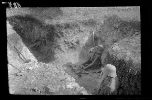 Übungsgelände II bei Mouzon (Dep. Ardennes, Frankreich): geladener [Minenwerfer] in einer Grube, im Vordergrund in Deckung ein Soldat mit Stahlhelm
