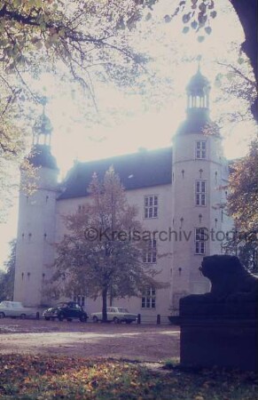 Ahrensburg: Schloss Ahrensburg: Blick auf Nordostfront: davor parkende Pkws und Baum: vorn rechts steinerner Löwe auf Sockel: links Zufahrtsweg